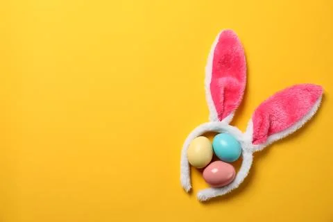 Funny headband with Easter bunny ears and dyed eggs on color background, flat Stock Photos