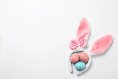 Funny headband with Easter bunny ears and dyed eggs white background, top vie 스톡 사진