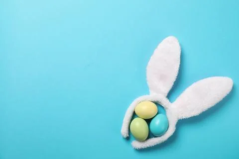 Funny headband with Easter bunny ears and dyed eggs on color background, flat Stock Photos