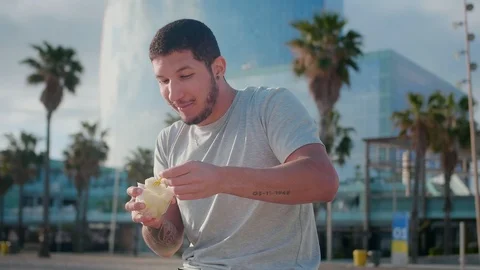 Funny Hispanic guy sitting and enjoying fresh fruits at modern city area with Stock-Footage 108443638