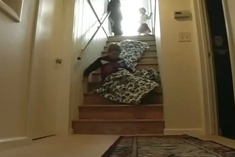 Funny home video of a boy riding on a blanket down the stairs in home. Stock Footage 107281069