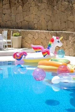 Funny inflatable unicorn ring floating in swimming pool on sunny day. Swimming Stock Photos