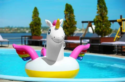 Funny inflatable unicorn ring floating in swimming pool on sunny day, outdoor 写真素材