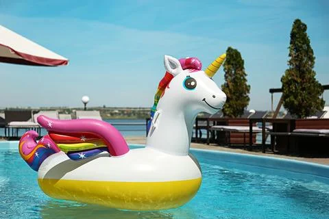 Funny inflatable unicorn ring floating in swimming pool on sunny day, outdoor Foto stock