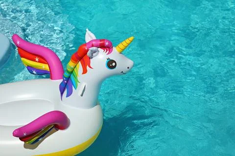 Funny inflatable unicorn ring floating in swimming pool on sunny day. Space f Foto stock