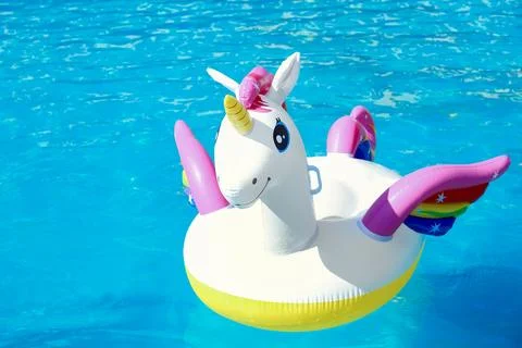 Funny inflatable unicorn ring floating in swimming pool on sunny day Foto stock