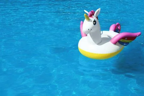 Funny inflatable unicorn ring floating in swimming pool on sunny day. Space f 스톡 사진