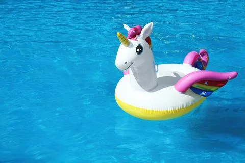 Funny inflatable unicorn ring floating in swimming pool on sunny day. Space f Foto stock