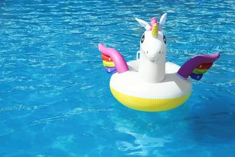 Funny inflatable unicorn ring floating in swimming pool on sunny day. Space f Foto stock