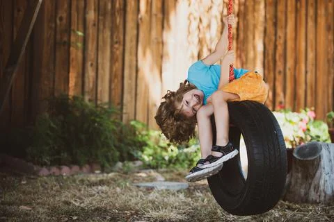 Funny kid boy having fun with chain swing on outdoor playground. Child playing 写真素材