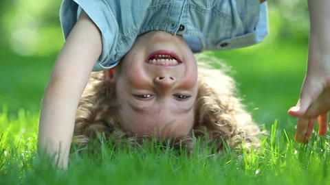 Funny kid do a handstand in a summer park on green grass. Slow motion Stock Footage 335825973
