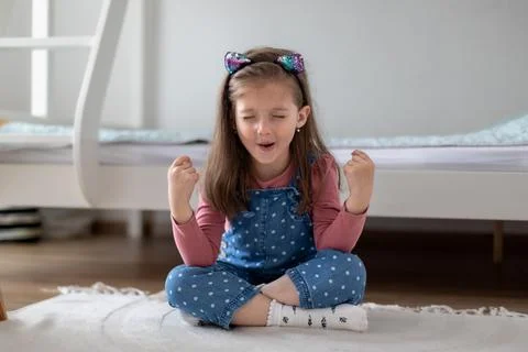 Funny kid doing yoga exercise at home. Little girl sitting in a yoga pose Stock-Fotos