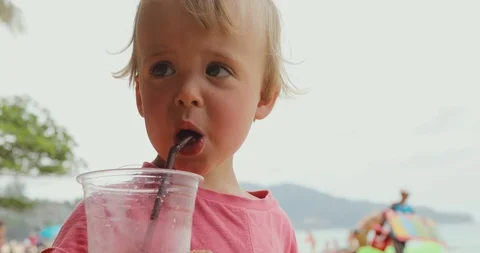 Funny kid drinking on beach Stock Footage 100022093