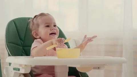Funny kid eats and laughs while sitting at a table at home Stock Footage 156472650