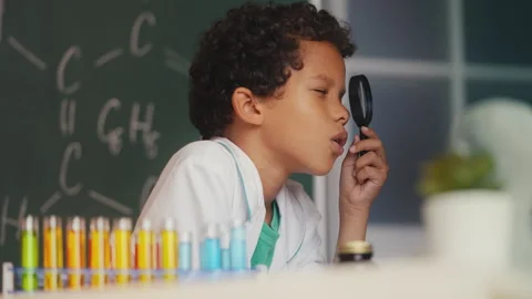 Funny kid examining plant sample with a magnifying glass, surprised with results Video stock 279880423