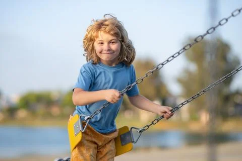 Funny kid on swing. Little boy swinging on playground. Happy cute excited child Stock Photos