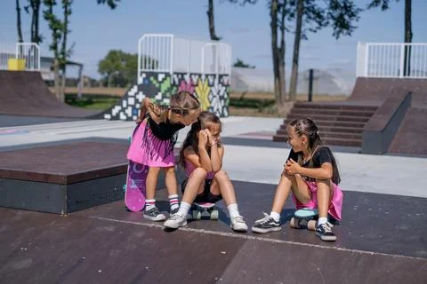 Funny kids chat while sitting on skateboards at the fun pyramids boxes of the Foto stock
