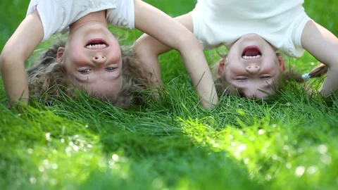 Funny kids do a handstand in a summer park on green grass. Slow motion Stock Footage 335826050