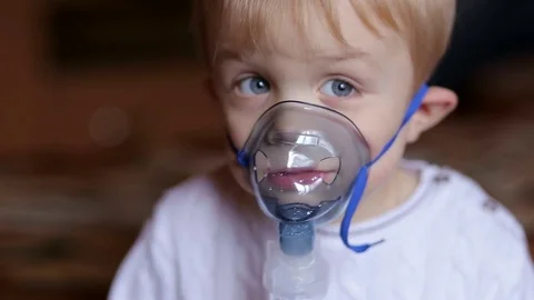 Funny little boy making inhalation with electronic nebulizer. Stock Footage 70516844