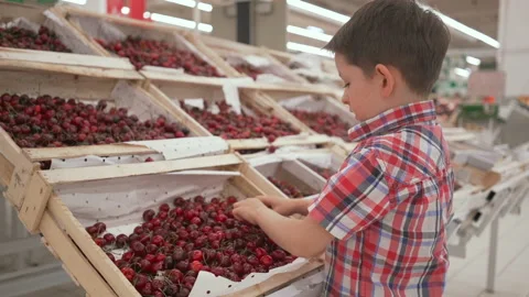 Funny little boy picking cherry from the box during family shopping in Stock Footage 90249227