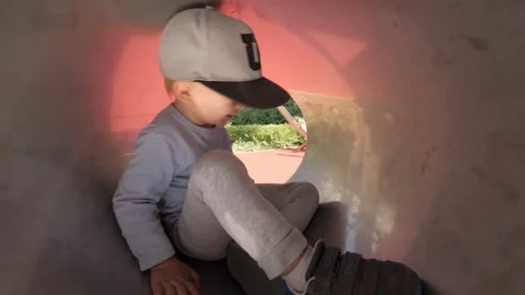 Funny little boy playing in pipe slide attraction at child playground laughing Stock Footage 155417635