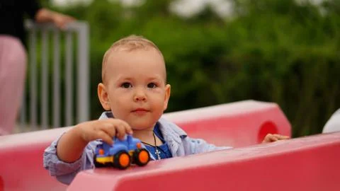 Funny little boy sitting among the plastic rose fences in the playground Foto stock