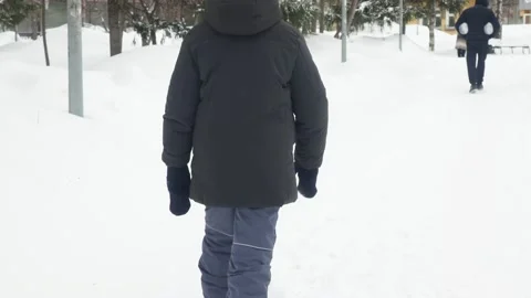 Funny little boy in winter clothes walks during a snowfall. Outdoors Stock Footage 150520386