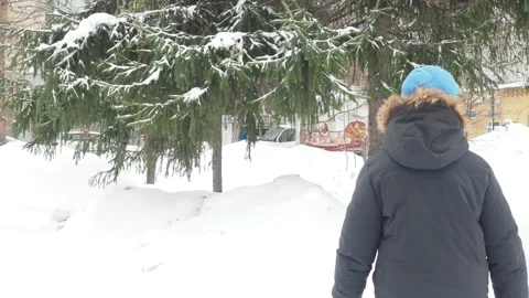 Funny little boy in winter clothes walks during a snowfall. Outdoors Stock Footage 150520502