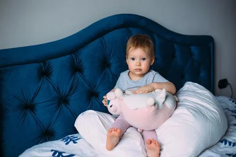 Funny little child is having fun, playing with soft toys on the couch at home. Fotos Stock