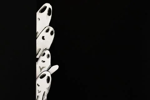 Funny little ghosts scaring behind a wall.Paper art.Dark background. Illustrazione stock