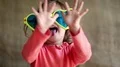Funny little girl in big glasses looks at camera, shows his hands and tongue HD Footage
