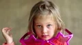 Funny little girl in big pink glasses in the shape of stars looks at the camera HD Footage
