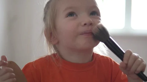 Funny little girl does makeup for herself with a blush brush Stock Footage 101596910