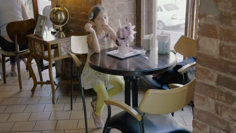 Funny little girl eats dessert and looks into the camera Stock Footage 111275868