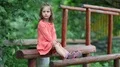 Funny little girl sits on a wooden log at a sports ground HD Footage