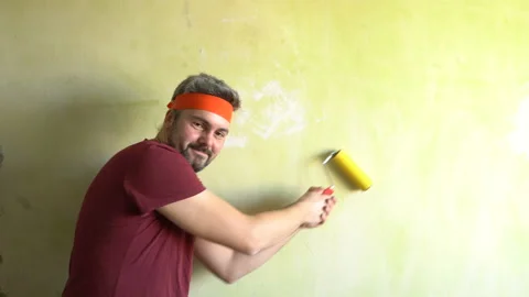 Funny man with a beard is dancing with a wallpaper roller 4K Video stock 126126016