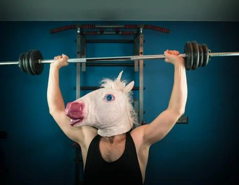 Funny man in comical mask doing sport exercise Stock Photos