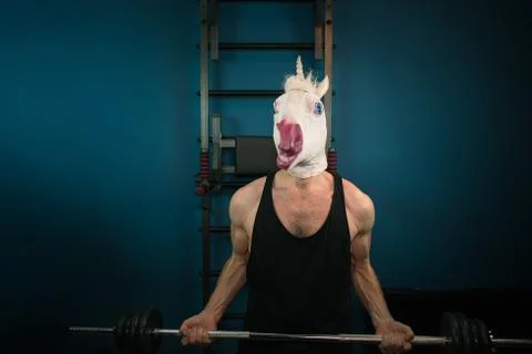 Funny man in comical mask doing sport exercise. Unusual guy pump up iron Stock Photos