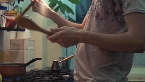 Funny man cooking meal dancing with spatulas in front of stove at kitchen Stock Footage 83090404
