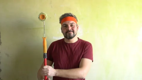 Funny man dancing with a construction roller on a wall background 4K Stock Footage 126126244