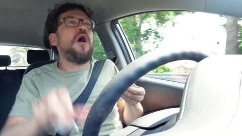 Funny man dancing eating hamburger while driving car 4K Stock Footage 77620119