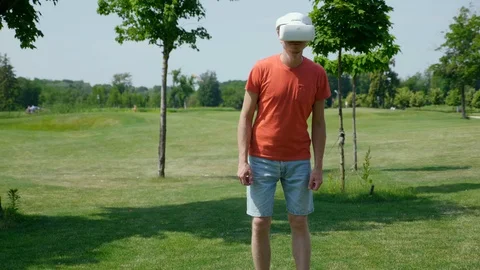 Funny man is dancing in the park in a virtual reality helmet Stock Footage 128829805