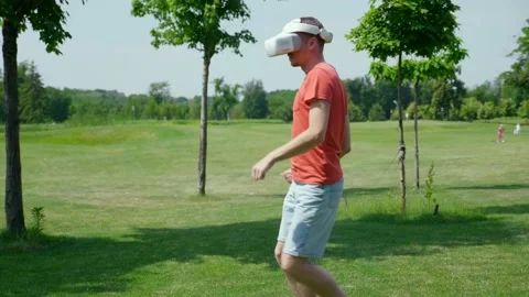 Funny man is dancing in the park in a virtual reality helmet Stock Footage 130775357