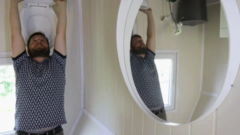 Funny Man Doing Pull-Up Exercise With Toilet Bowl In Upside Down Bathroom. Stock Footage 284073464