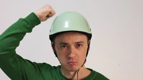 Funny man in a helmet punching himself on the head Stock Footage 344057355