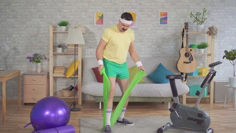 Funny man loser who does fitness at home with the help of elastic bands Stock Footage 108616580