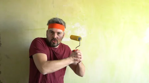 Funny man moves his hands and plays with a wallpaper roller 4K Stock Footage 126125985