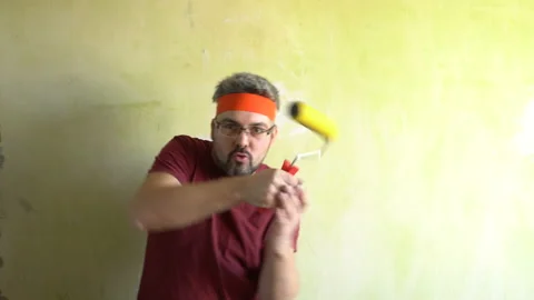Funny man plays with a wallpaper roller 4K Stock Footage 126125935