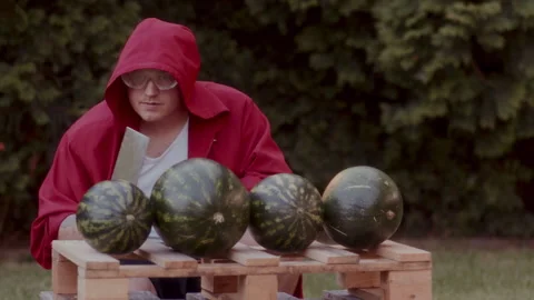 A Funny man in a red coat with safety goggles slicing up the watermelons Vidéo 258317281
