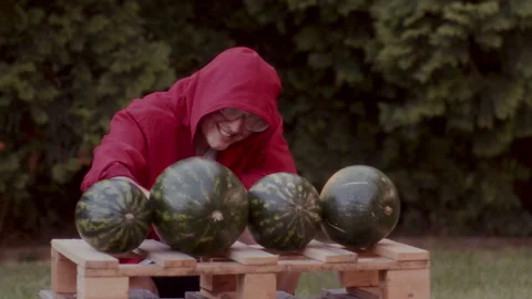 Funny man in a red coat with safety goggles slicing up the watermelons Video stock 258317593